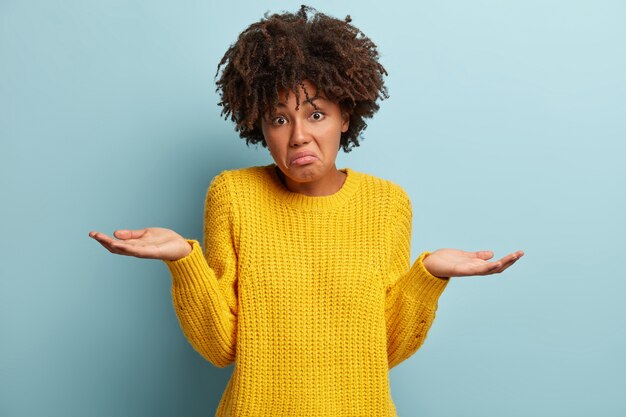 Junge Frau mit Afro-Haarschnitt, der gelben Pullover trägt