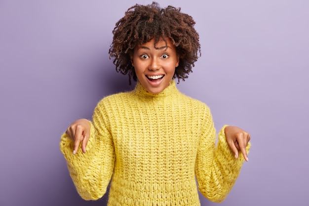 Junge Frau mit Afro-Haarschnitt, der gelben Pullover trägt