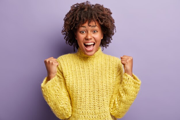 Junge Frau mit Afro-Haarschnitt, der gelben Pullover trägt