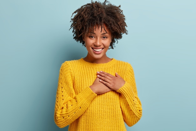 Junge Frau mit Afro-Haarschnitt, der gelben Pullover trägt