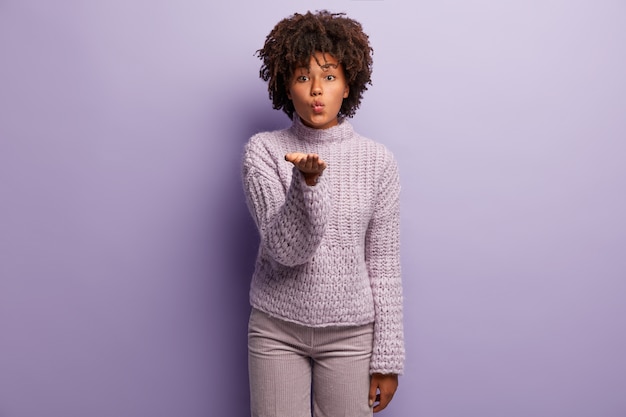 Junge Frau mit Afro-Haarschnitt, der lila Pullover trägt