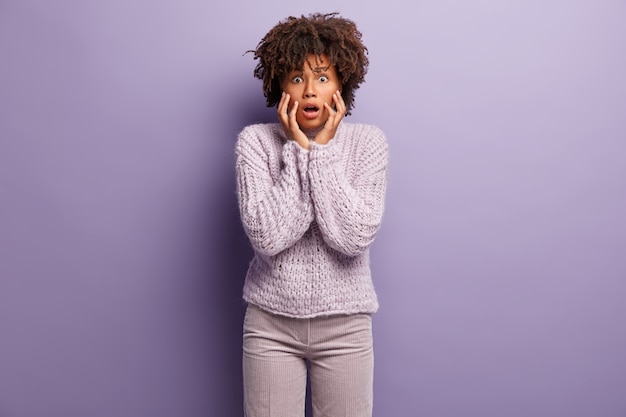 Junge Frau mit Afro-Haarschnitt, der lila Pullover trägt