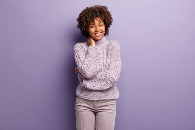 Junge Frau mit Afro-Haarschnitt, der lila Pullover trägt