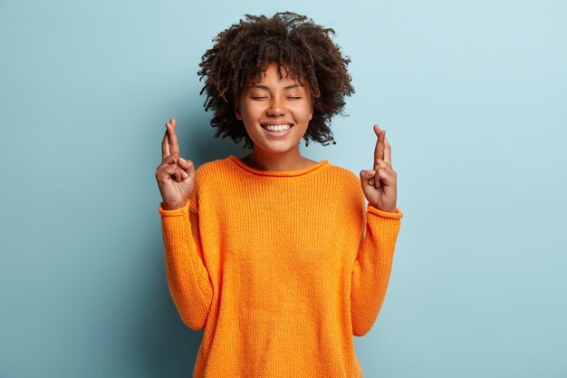 Junge Frau mit Afro-Haarschnitt, der orange Pullover trägt