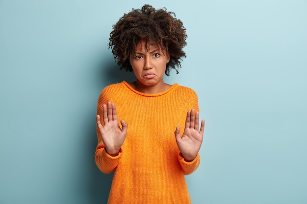 Kostenloses Foto junge frau mit afro-haarschnitt, der orange pullover trägt