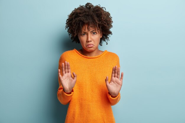 Junge Frau mit Afro-Haarschnitt, der orange Pullover trägt