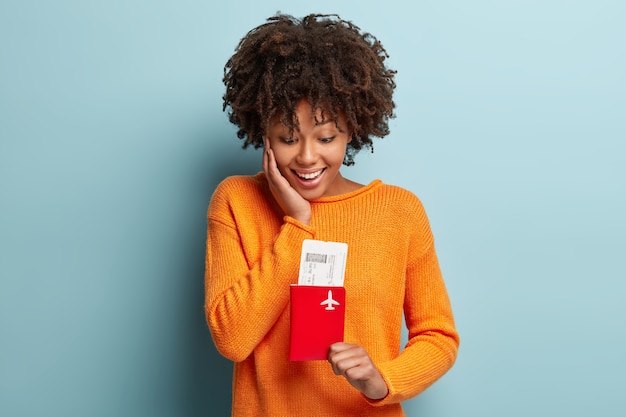 Junge Frau mit Afro-Haarschnitt, der orange Pullover trägt