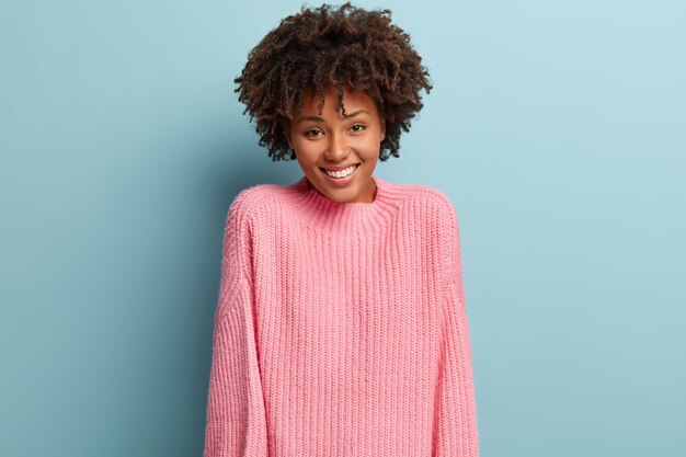 Junge Frau mit Afro-Haarschnitt, der rosa Pullover trägt
