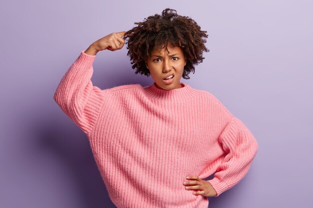 Junge Frau mit Afro-Haarschnitt, der rosa Pullover trägt