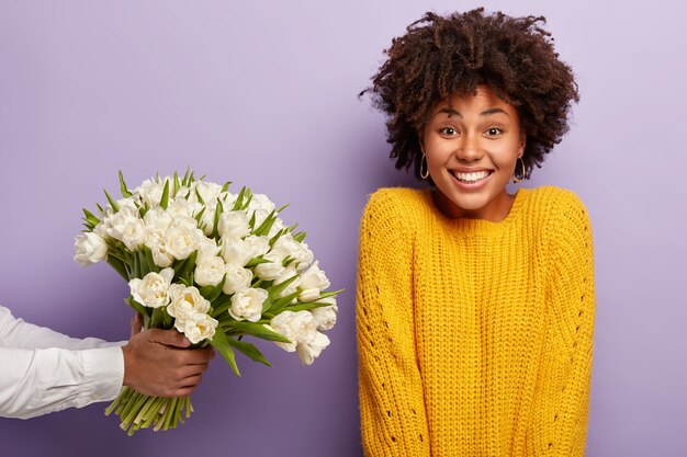 Junge Frau mit Afro-Haarschnitt, der Strauß der weißen Blumen empfängt