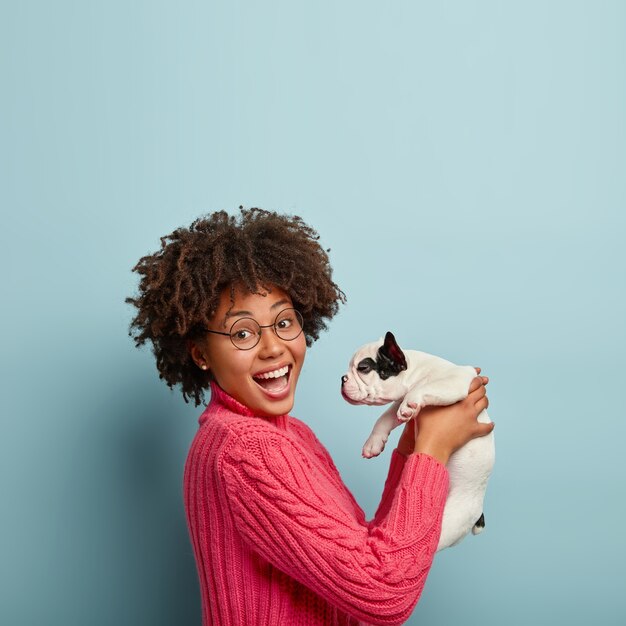 Junge Frau mit Afro-Haarschnitt, der Welpen hält