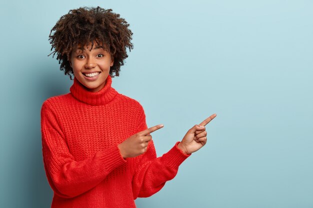 Junge Frau mit Afro-Haarschnitt, die roten Pullover trägt