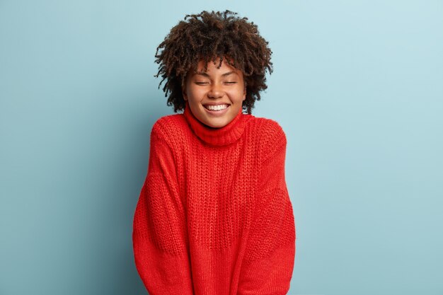 Junge Frau mit Afro-Haarschnitt, die roten Pullover trägt