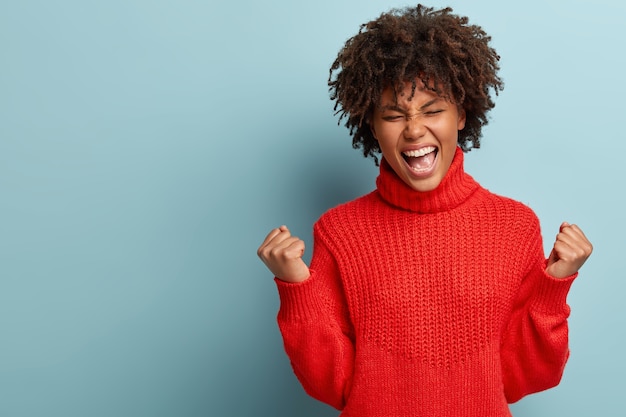 Junge Frau mit Afro-Haarschnitt, die roten Pullover trägt