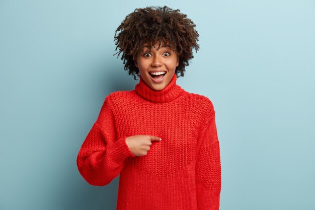 Junge Frau mit Afro-Haarschnitt, die roten Pullover trägt