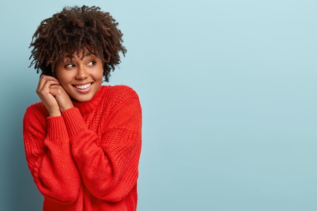 Junge Frau mit Afro-Haarschnitt, die roten Pullover trägt