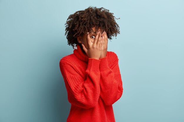 Junge Frau mit Afro-Haarschnitt, die roten Pullover trägt