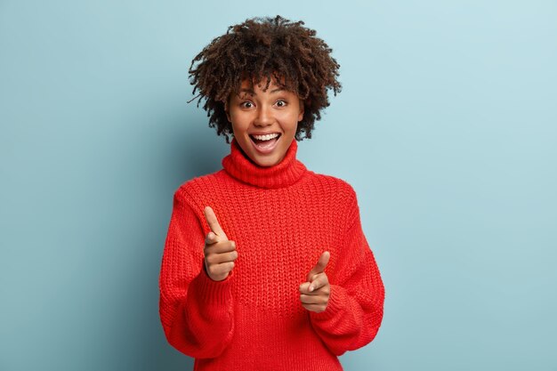 Junge Frau mit Afro-Haarschnitt, die roten Pullover trägt