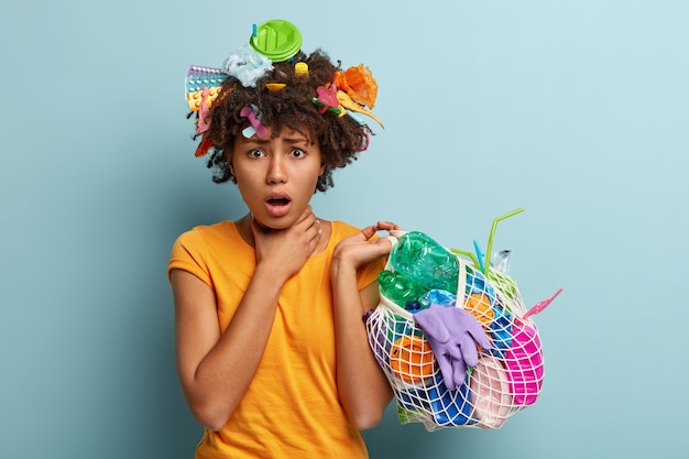 Junge Frau mit Afro-Haarschnitt, die Tasche mit Plastikmüll hält