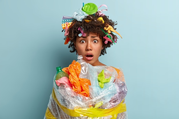 Kostenloses Foto junge frau mit afro-haarschnitt, die tasche mit plastikmüll hält