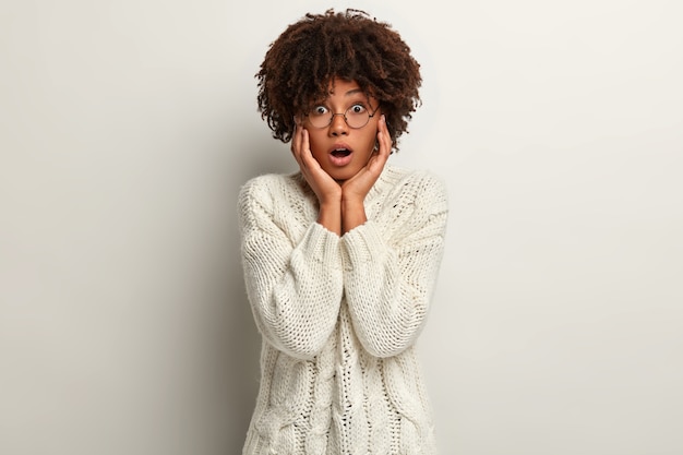 Junge Frau mit Afro-Haarschnitt, die weißen Pullover trägt