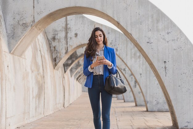 Junge Frau mit blauen Jacke ihr Handy überprüft