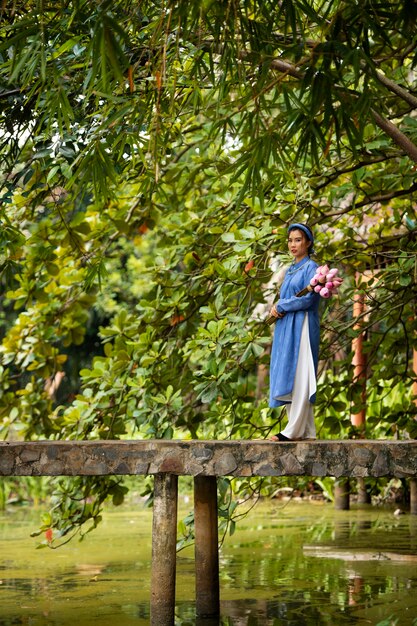 Junge Frau mit Blumenstrauß im Ao-Dai-Kostüm