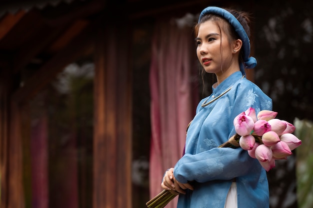 Junge Frau mit Blumenstrauß im Ao-Dai-Kostüm