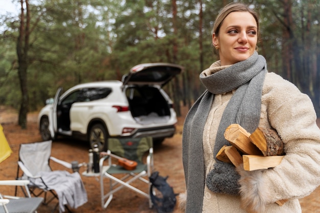 Kostenloses Foto junge frau mit brennholz für lagerfeuer beim camping