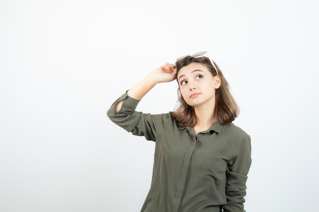 Junge Frau mit Brille, die irgendwo steht und schaut. Foto in hoher Qualität