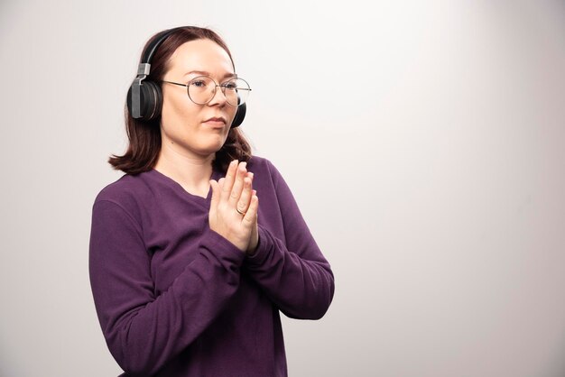 Junge Frau mit Brille, die Musik über Kopfhörer auf einem Weiß hört. Foto in hoher Qualität