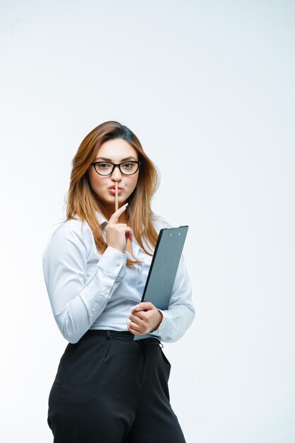 Junge Frau mit Brille, die Stillegeste mit Stift zeigt