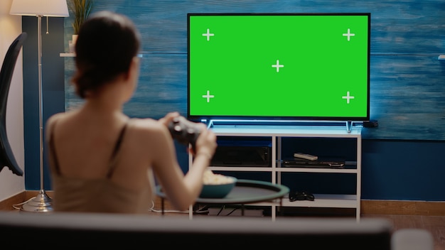 Junge frau mit controller auf grünem bildschirm im fernsehen