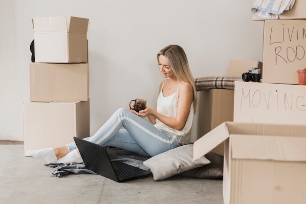 Junge Frau mit dem Kaffee, der auf dem Boden sitzt