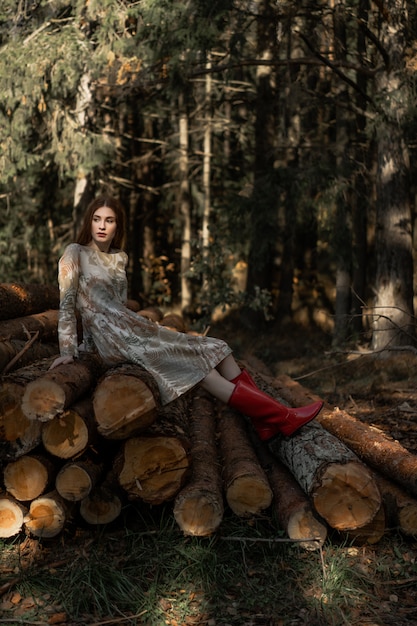 Junge Frau mit dem langen roten Haar in einem Leinenkleid Pilze im Wald erfassend