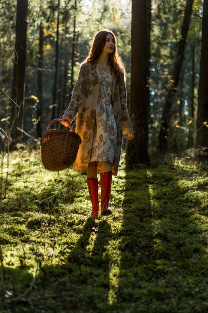 Junge Frau mit dem langen roten Haar in einem Leinenkleid Pilze im Wald erfassend