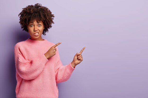 Junge Frau mit dem lockigen Haar, das rosa Pullover trägt