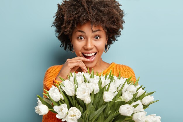 Junge Frau mit dem lockigen Haar, das Strauß der weißen Blumen hält