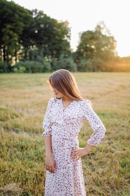 Junge Frau mit dem schönen Haar, das im Feld bei Sonnenuntergang aufwirft. Mode, Unabhängigkeit