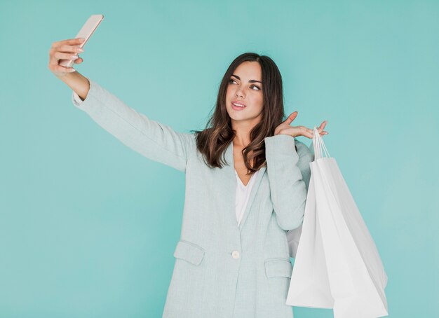 Junge Frau mit den Einkaufstaschen, die ein selfie nehmen