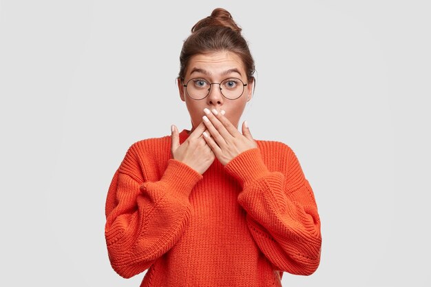 Junge Frau mit den Haaren in einem Brötchen, das einen roten Pullover trägt