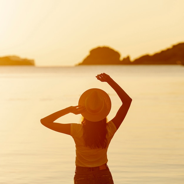 Kostenloses Foto junge frau mit einem hut auf sonnenuntergang