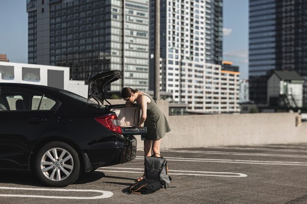 Junge Frau mit einem Koffer offen im Kofferraum des Autos