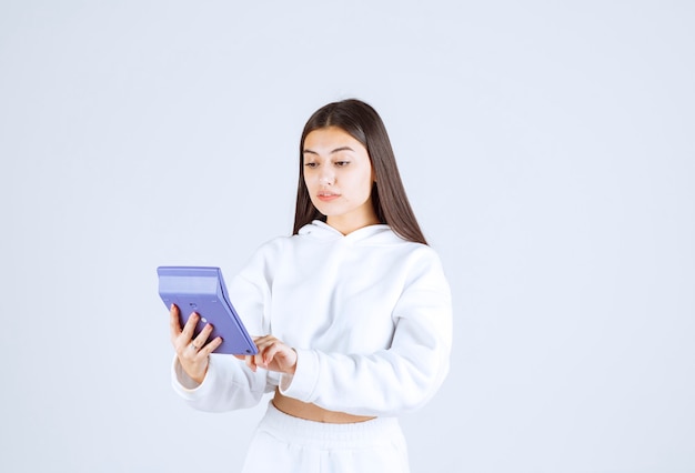 junge Frau mit einem Taschenrechner auf weiß-grauem Hintergrund.