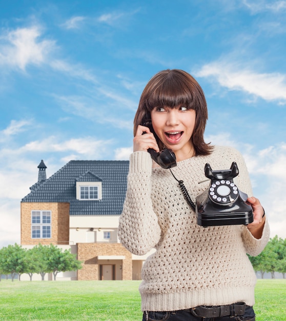 Kostenloses Foto junge frau mit einem vintage telefon sprechen im freien