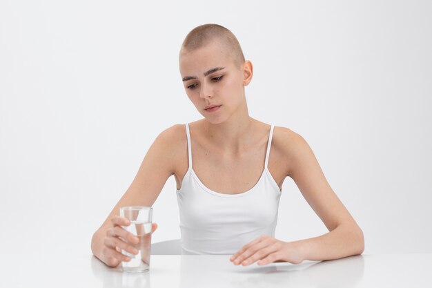 Junge Frau mit einer Essstörung schaut auf ein Glas Wasser