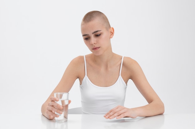 Junge Frau mit einer Essstörung schaut auf ein Glas Wasser