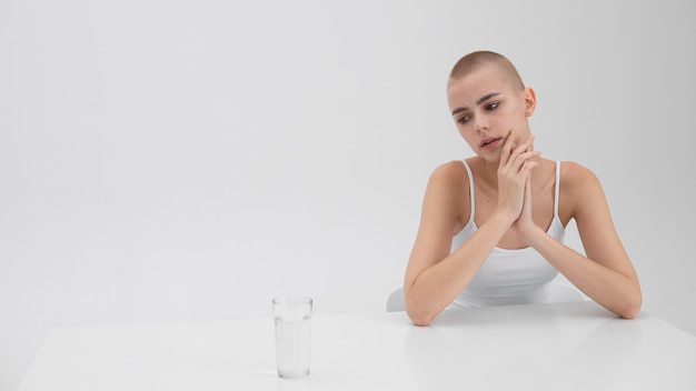 Junge Frau mit einer Essstörung schaut auf ein Glas Wasser