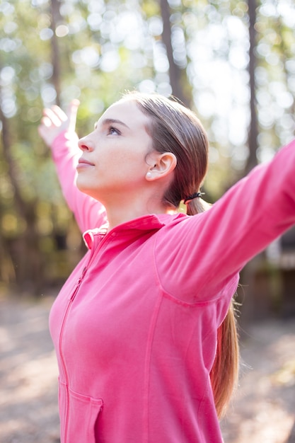 Junge Frau mit erhobenen Armen an einem sonnigen Tag