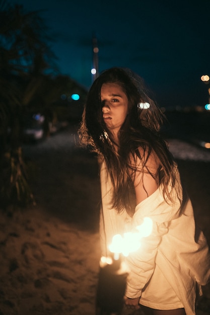 Junge Frau mit Fackelschein am Strand in der Nacht